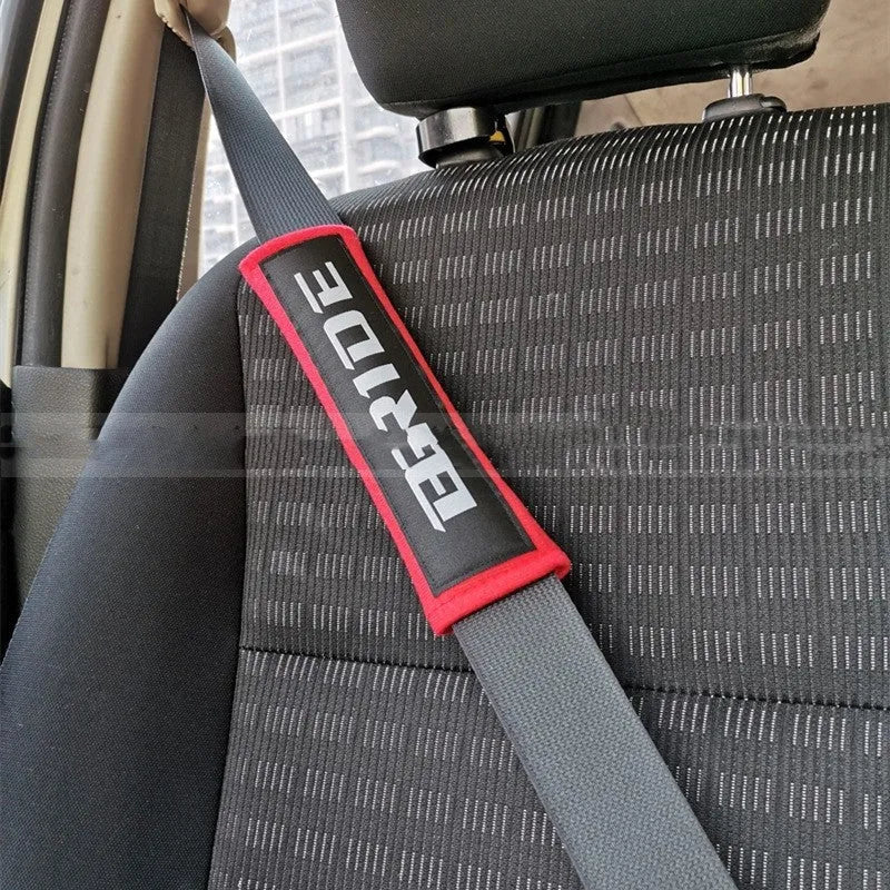 Pair of black car seatbelt shoulder pads made from cotton sponge cloth, showing embroidery detail.