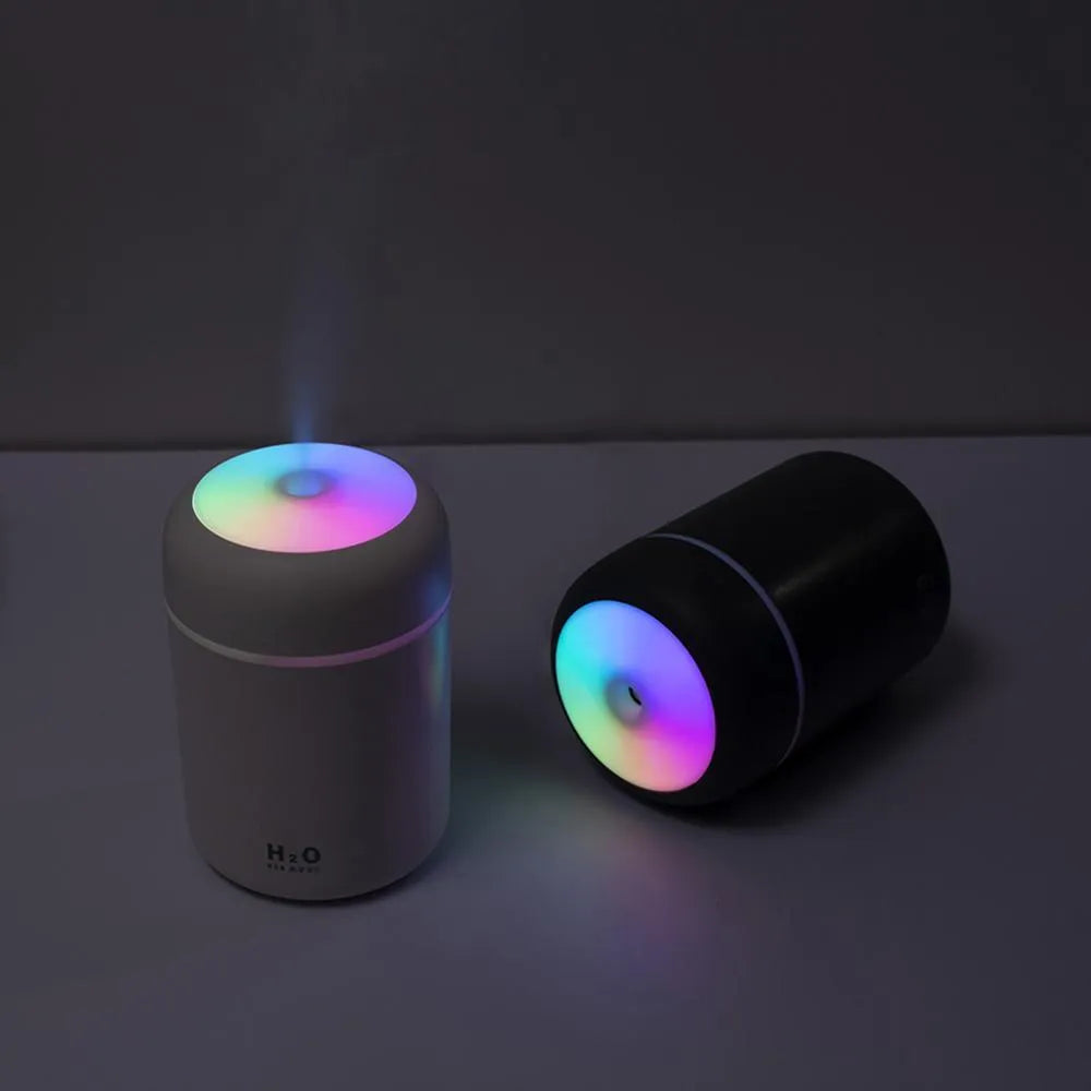 Pink USB desktop humidifier with mood lights and water tank on a wooden desk