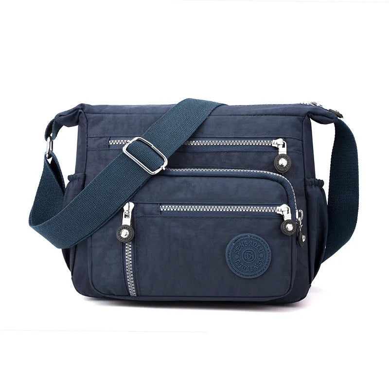 Soft nylon shoulder messenger bag in a square vertical shape with a single strap.