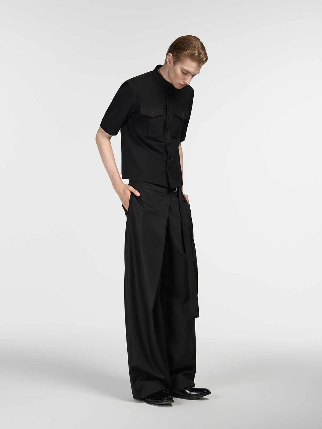 Black straight-leg trousers with single pleat front and adjustable waistband on hanger