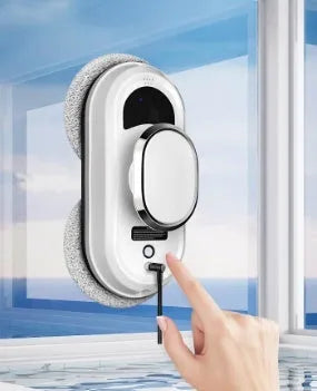 White automatic window cleaning machine with remote control and cleaning accessories on a windowsill