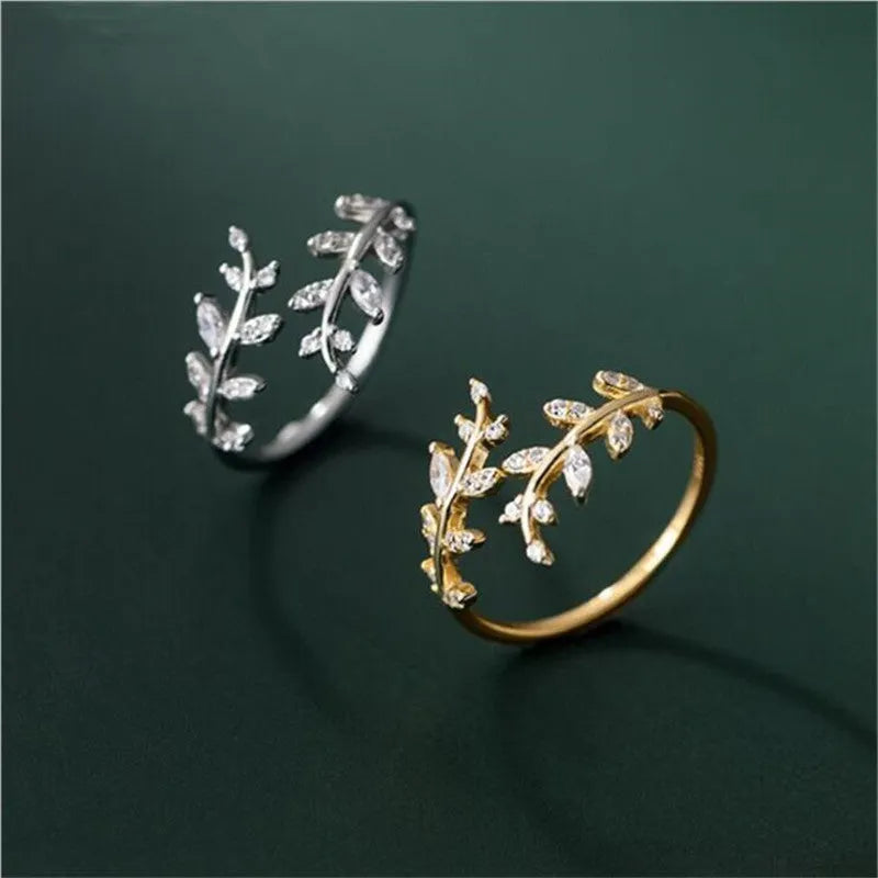 Gold and silver women's branch leaf fashion ring with geometric design on a plain background.