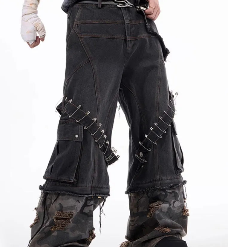 Men's grey cotton jeans with camouflage pattern splicing and decorative pin and ribbon details on the legs.