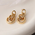 A pair of gold geometric drop earrings with an irregular asymmetric shape, made from copper.