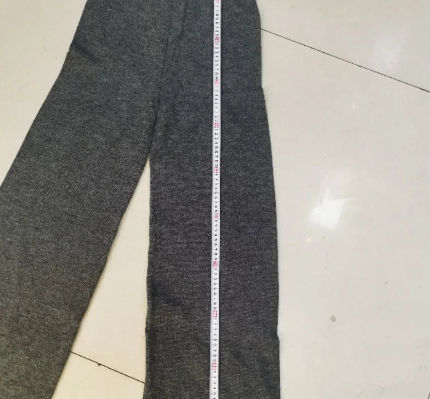 Women's dark grey acrylic knitted sweater with side slits and matching trousers.