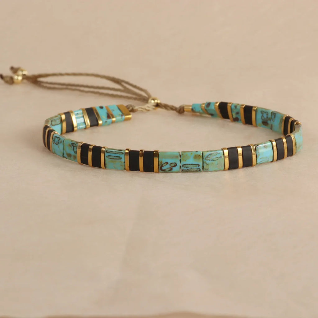 Geometric glass and coloured glaze beaded bracelet in milky white, black, green, blue, or red.