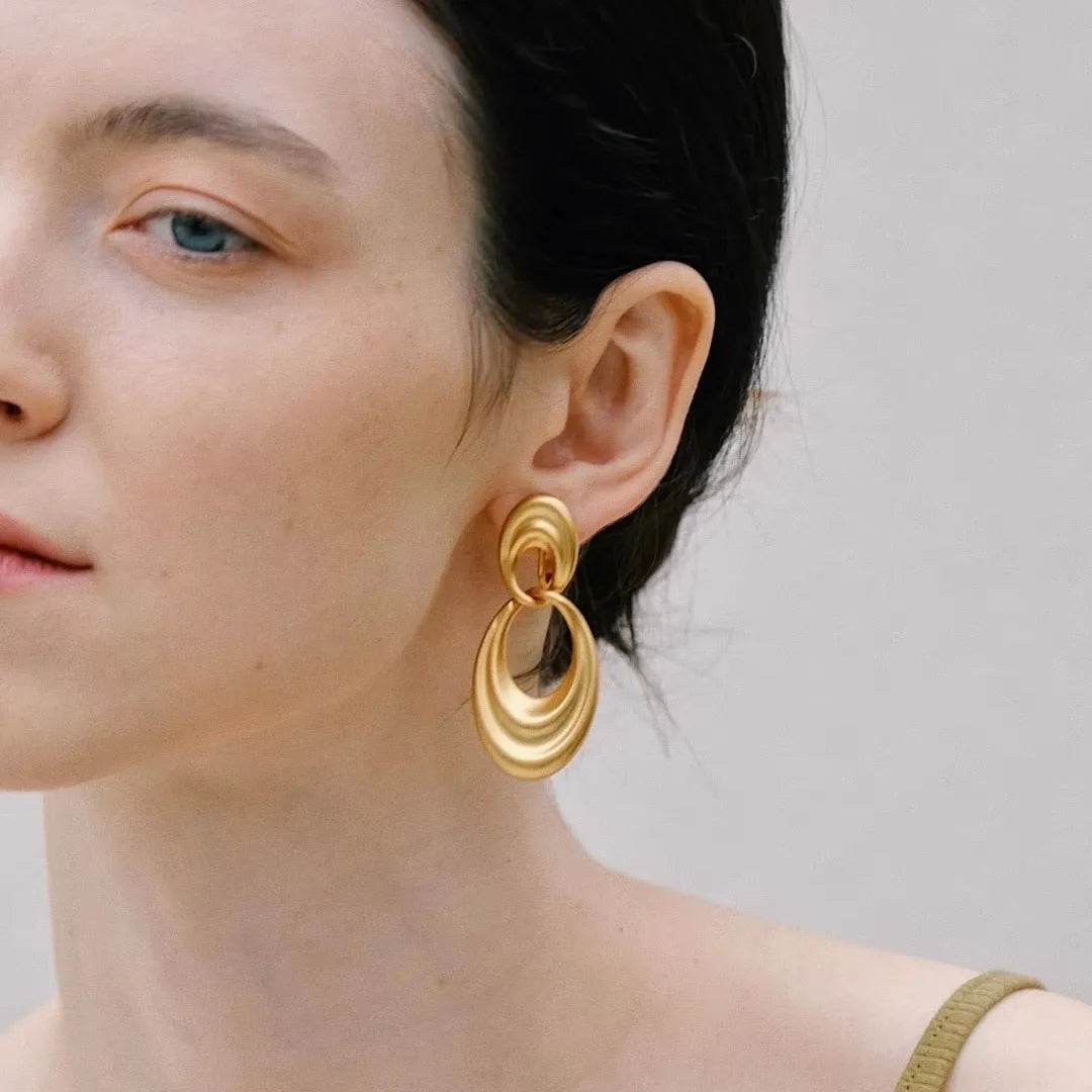 A pair of gold-toned double circle earrings with a textured quicksand finish on a copper base.