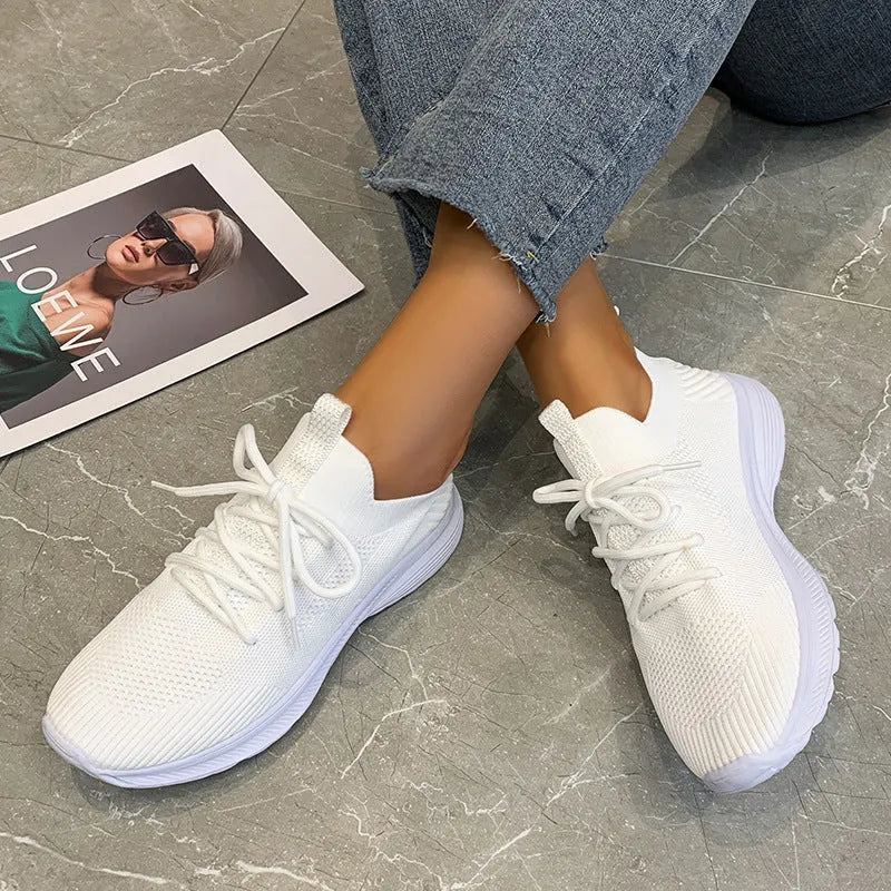 Women's low-top running shoes in creamy white with Flyknit upper and flat rubber sole.
