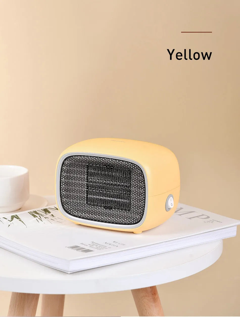 Mini green PTC ceramic fan heater on a desk showing compact size