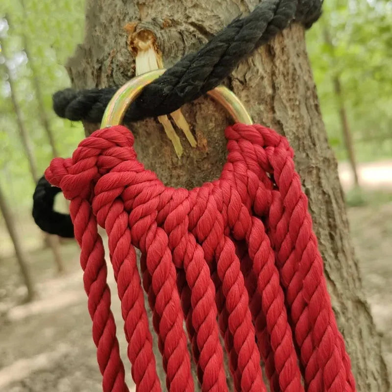 Nylon rope mesh hammock hung between two trees in a garden setting.