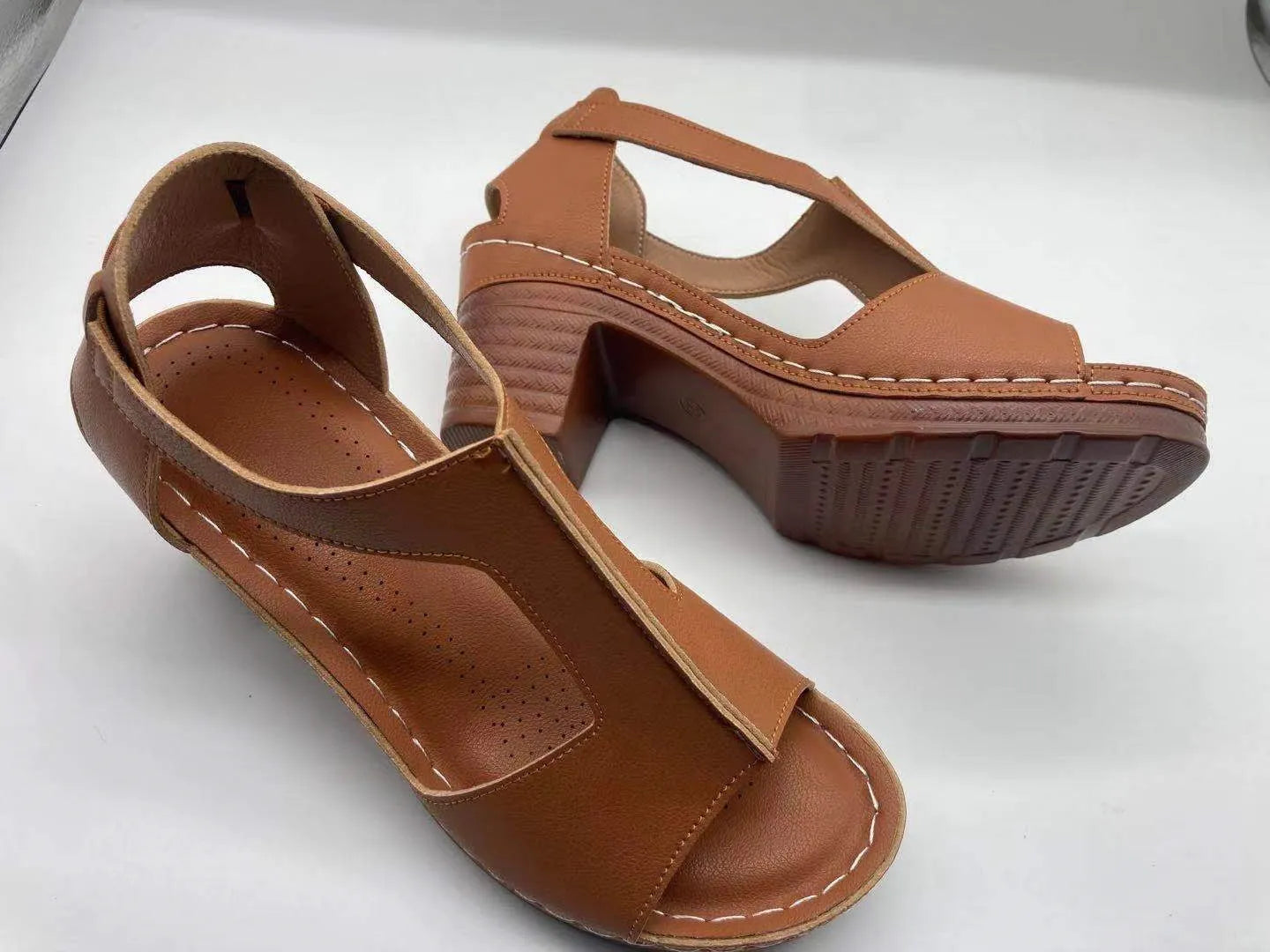 Women's white peep toe wedge sandals with a Roman-style buckle strap and low heel.