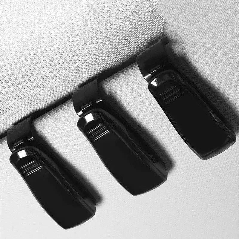 Black plastic multifunctional clip for car sun visors, designed to hold sunglasses and cards.