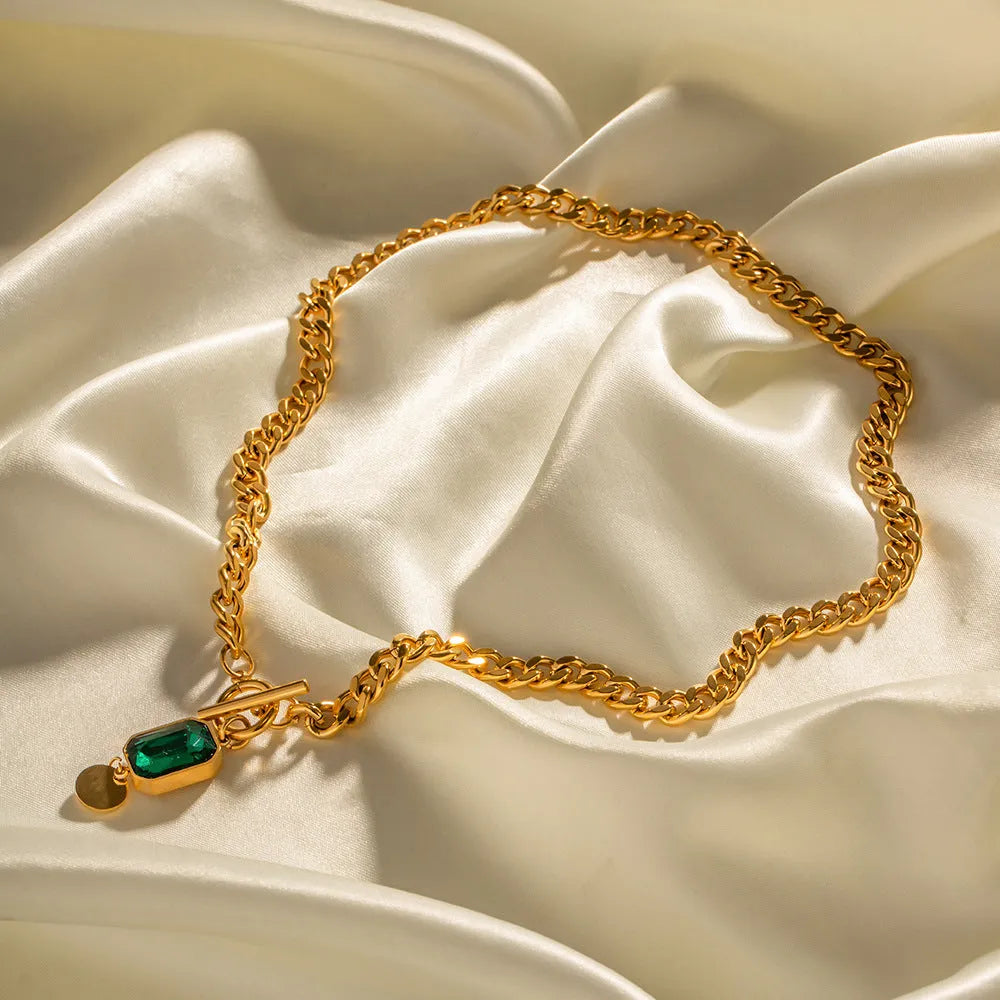 Gold titanium steel necklace with round emerald green zircon pendant on a Cuban link chain.