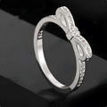 Silver bow-shaped ring with crystal zircon and rhinestone detailing on a finger
