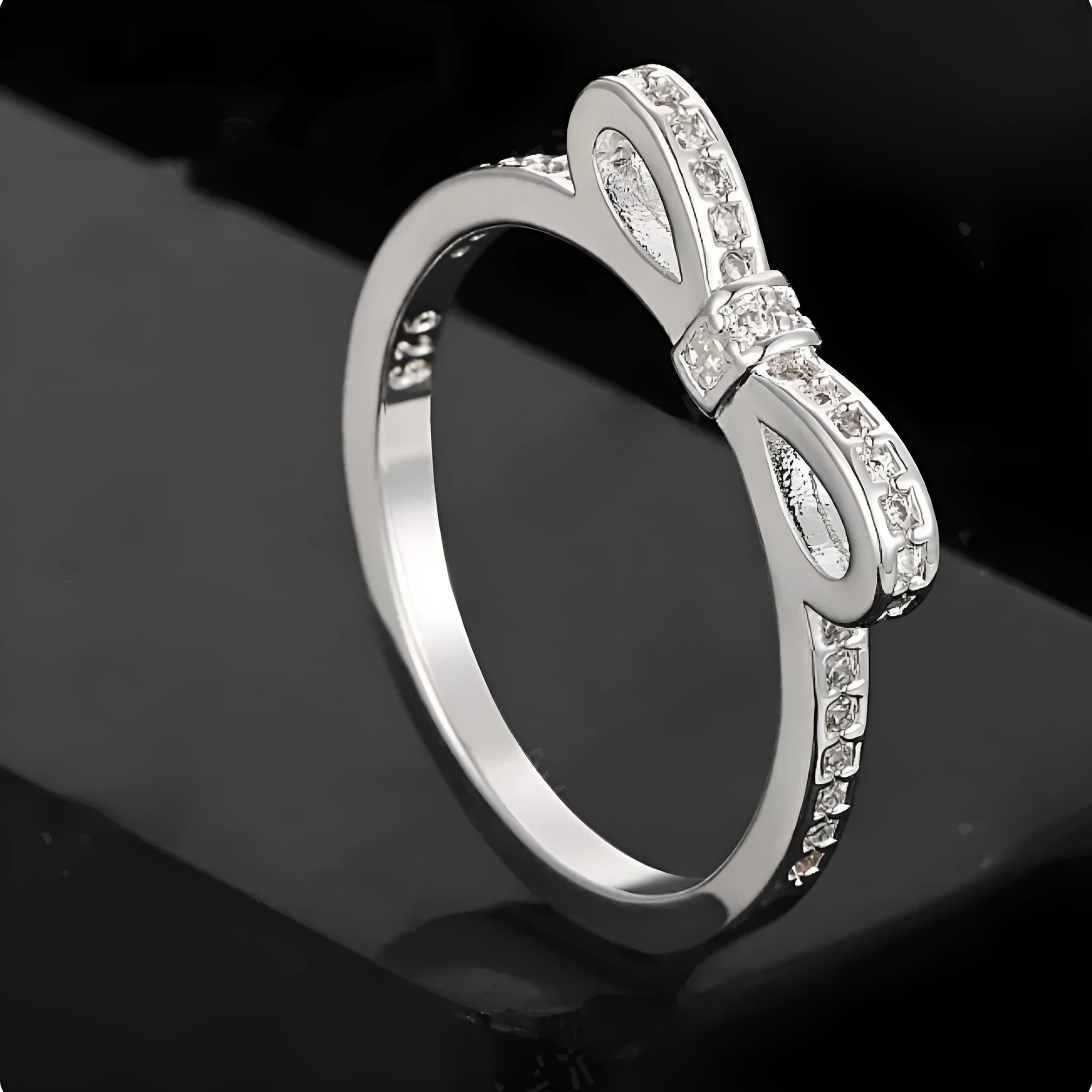 Silver bow-shaped ring with crystal zircon and rhinestone detailing on a finger