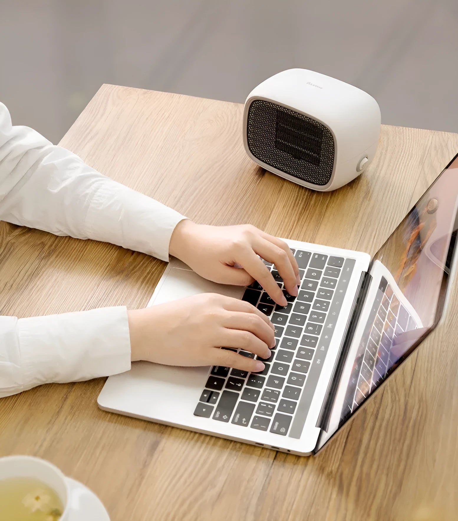 Mini green PTC ceramic fan heater on a desk showing compact size