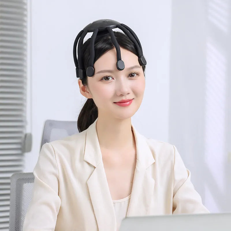Black or white electric head massager with multiple plastic claws for scalp vibration and relaxation.