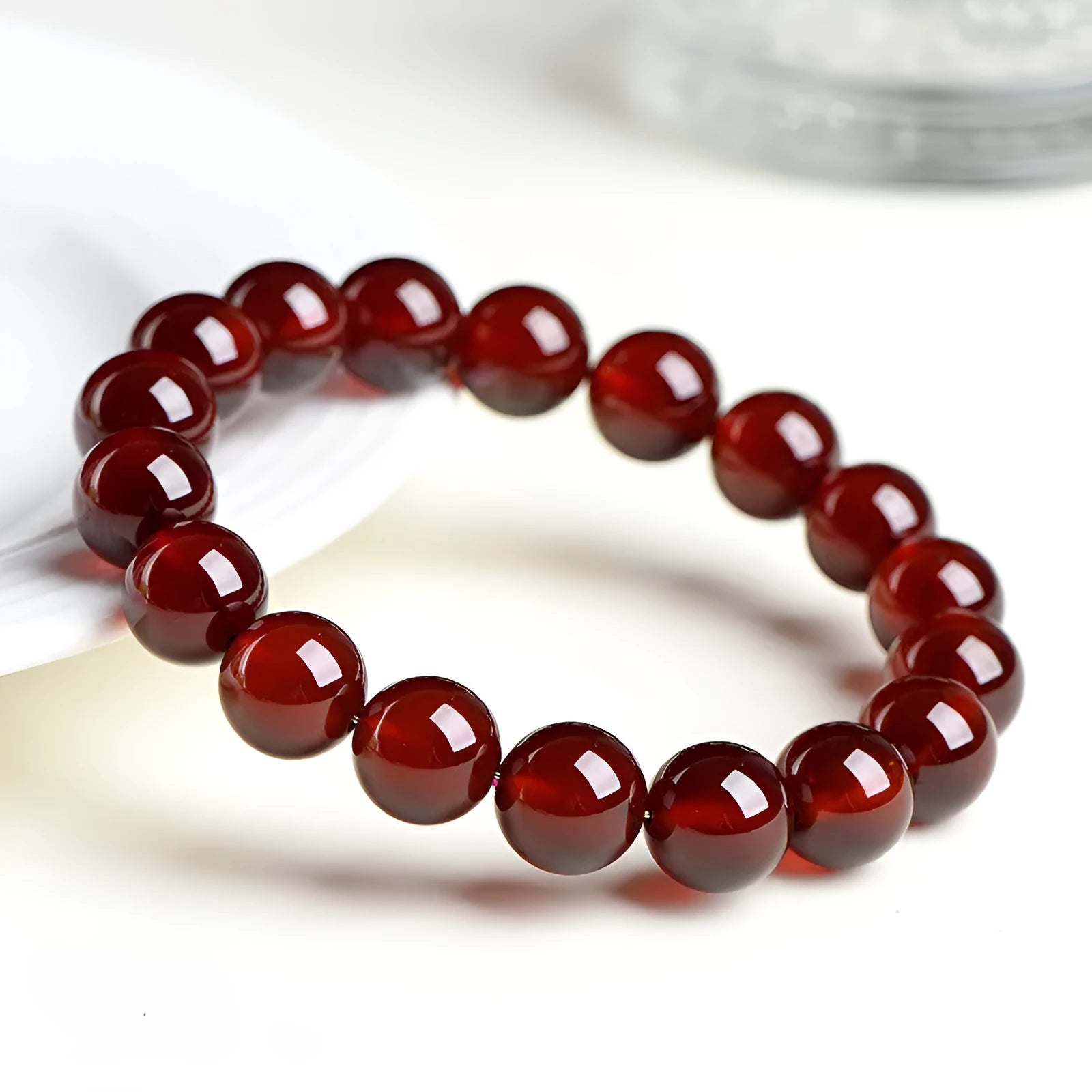 Natural orange red garnet ball bracelet with Ruyi elements on a wrist, showing retro unisex design.