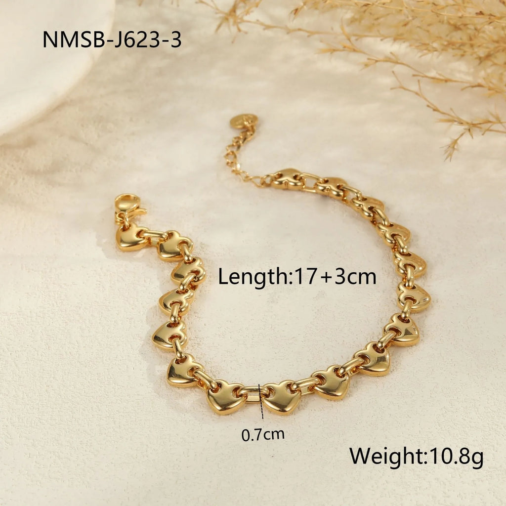 Hollowed-out stainless steel heart bracelet in gold finish on a wrist.