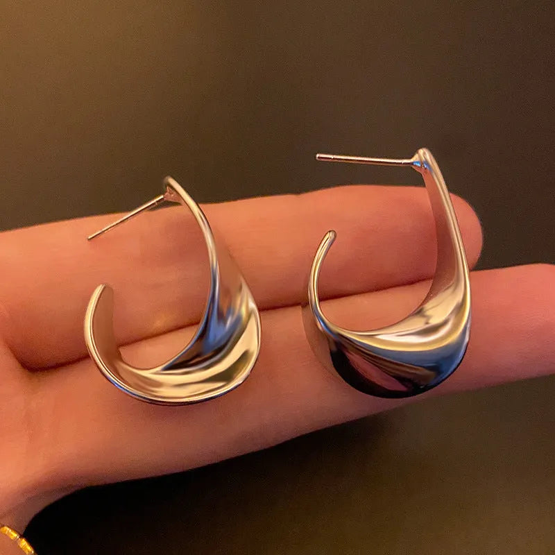 Geometric twisted metal earrings with electroplated gold or silver finish and round design elements