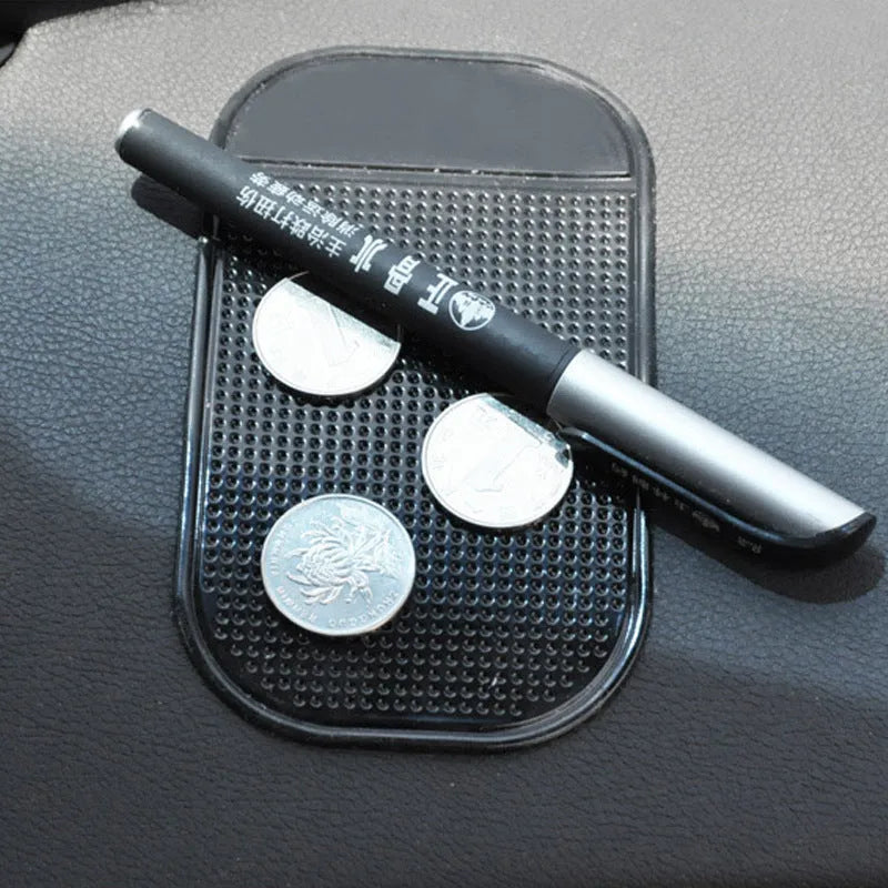 Black silicone car anti slip mat with spider-web texture, 13x7cm, on a car dashboard holding a smartphone