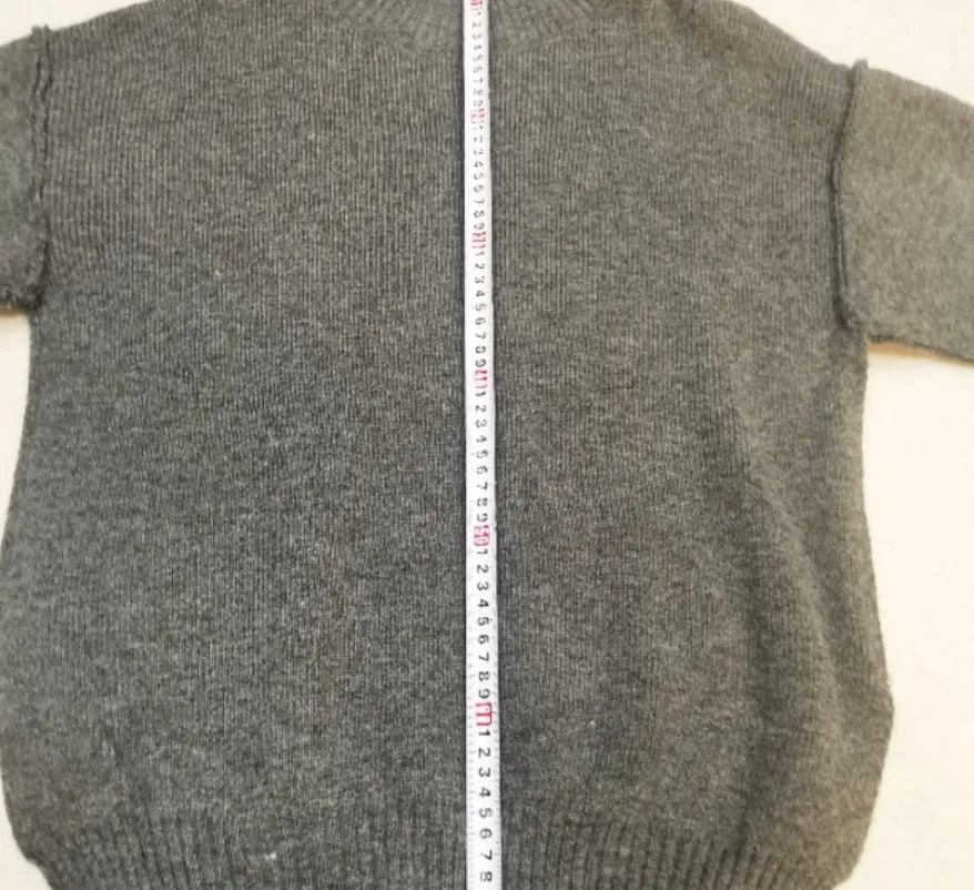 Women's dark grey acrylic knitted sweater with side slits and matching trousers.