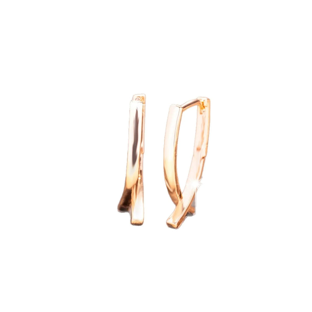 A pair of rose gold plated copper earrings in a cross shape on a plain background.