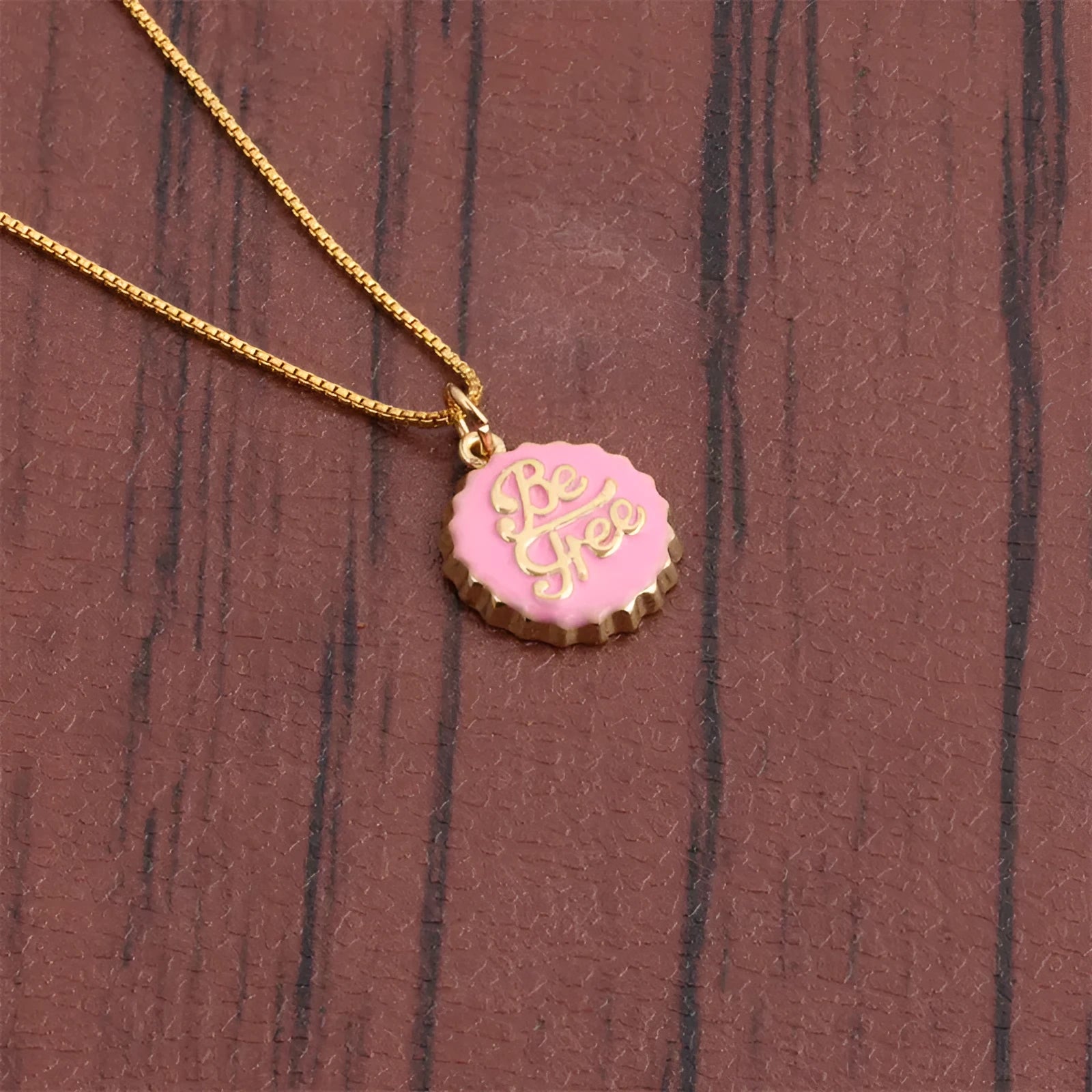 Copper bottle cap pendant necklace with 18k gold electroplating on a box chain, shown in one of six available colours.