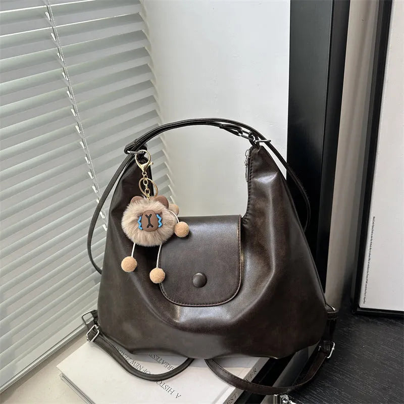 Black PU leather women's single strap shoulder bag showing horizontal square shape and internal mobile phone compartment