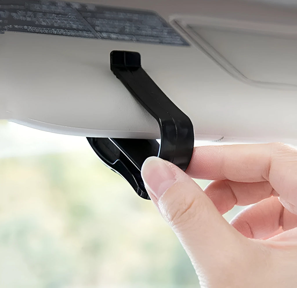 Black plastic multifunctional clip for car sun visors, designed to hold sunglasses and cards.