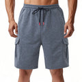 Men's light grey loose-fit terry cotton cargo shorts with multiple pockets on a plain background.