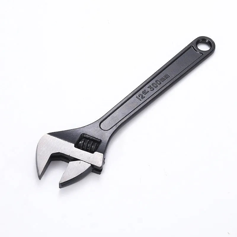 Blackened high carbon steel adjustable open-end wrench on a workbench, jaw set to mid-opening.