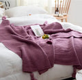 Nordic fringed knit ball acrylic blanket in beige, 130x170cm, draped on a sofa