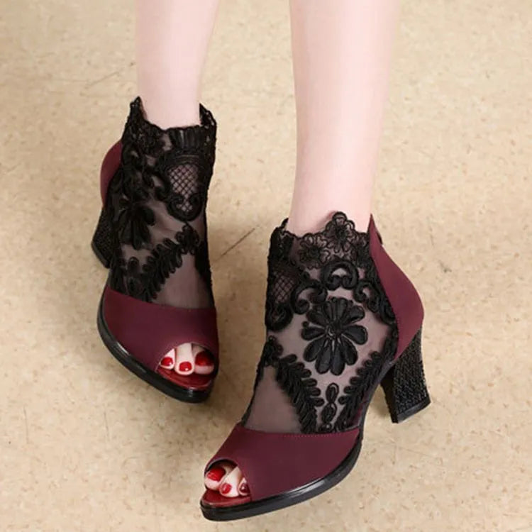 Black lace gladiator sandals with a square high heel, floral detail, and a zip closure at the ankle.