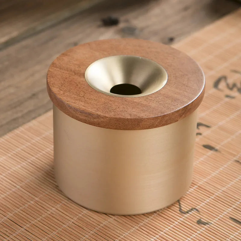 Retro brass and copper ashtray with wooden lid on a living room table.