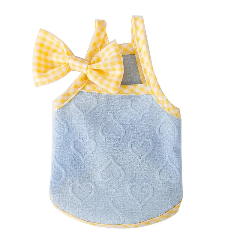 Small dog wearing a blue elastic vest with heart texture, suspenders, and a bow.