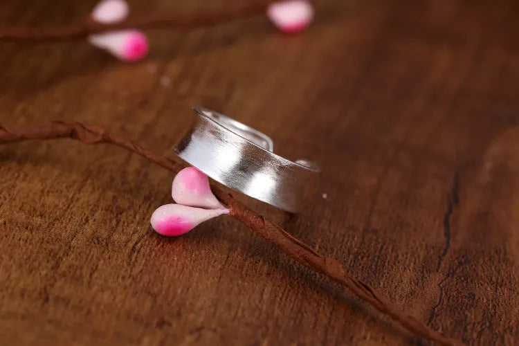 Geometric open ring in frosted sterling silver on a neutral background, showing adjustable opening.