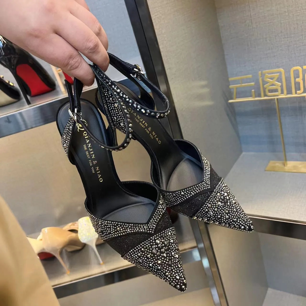 Women's black hollow high heel with stiletto heel, pointed toe, and red sole on a plain background.