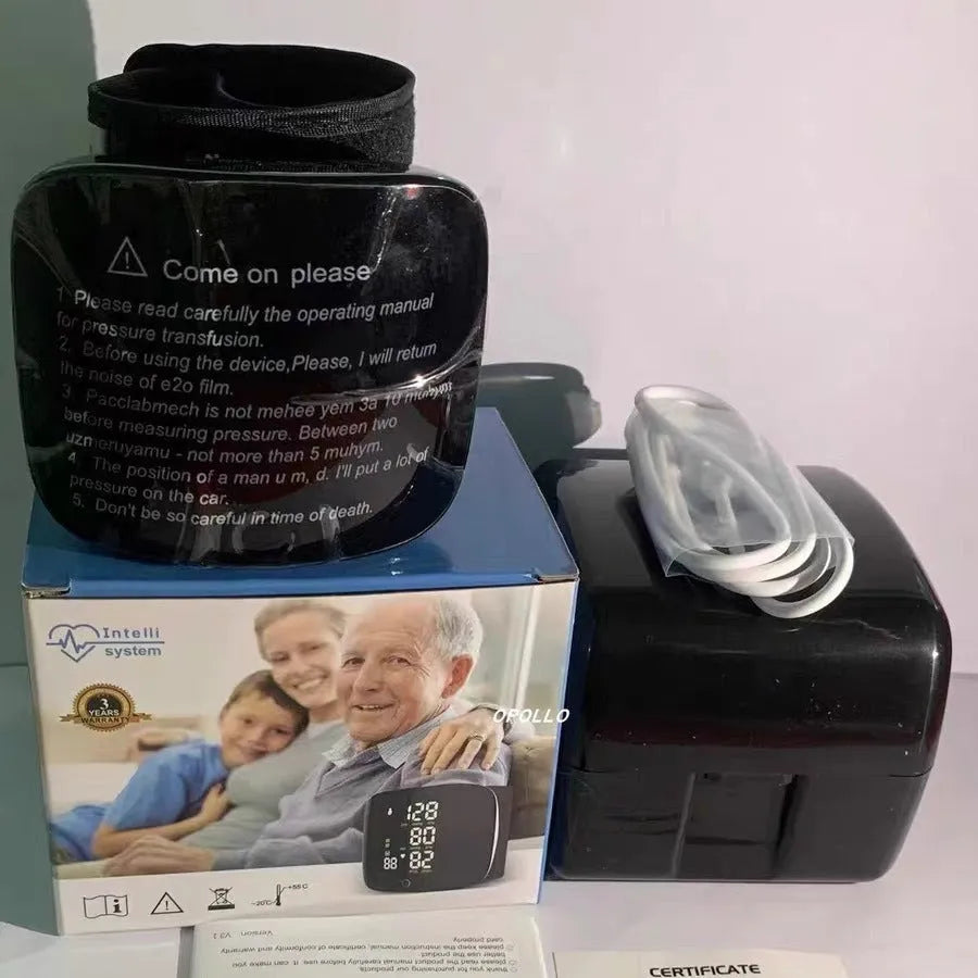 Black wrist blood pressure monitor with USB charging cable on a table.