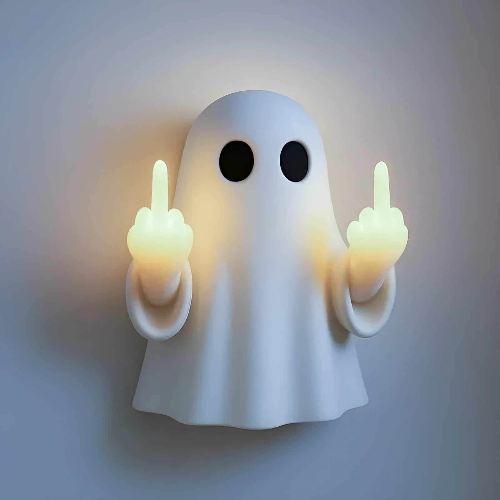 White plastic ghost night lamp with light on, on a flat surface