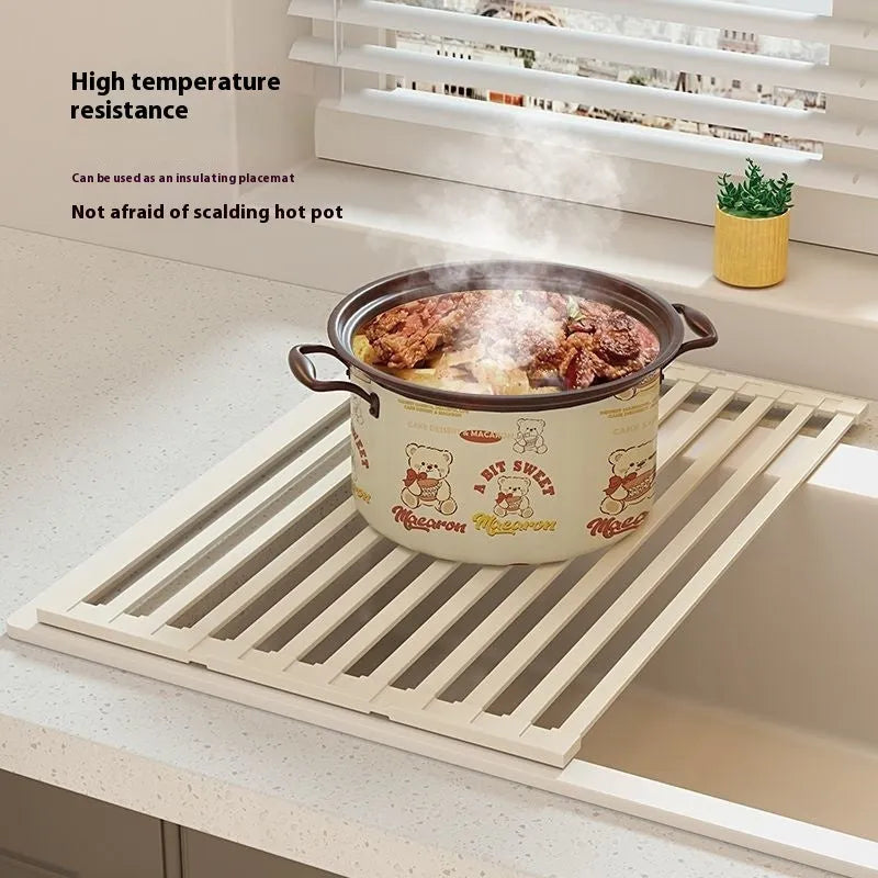 Milky white tri-fold stainless steel kitchen draining rack shown unfolded next to a sink.