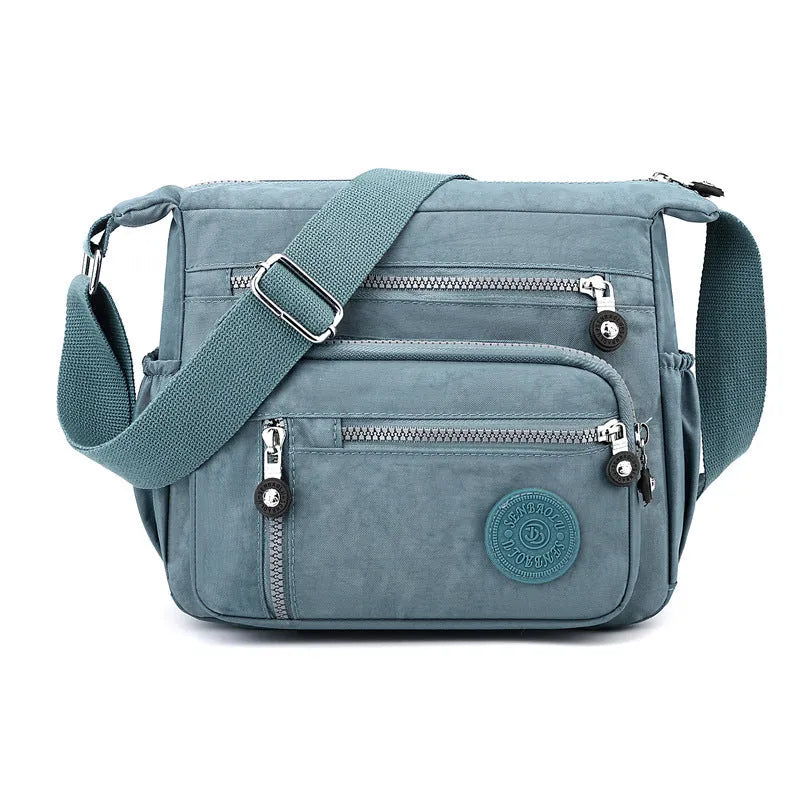 Soft nylon shoulder messenger bag in a square vertical shape with a single strap.