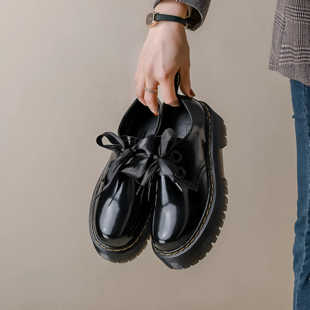 Women's white lace-up leather shoes with thick soles and black cross straps on the ankle.