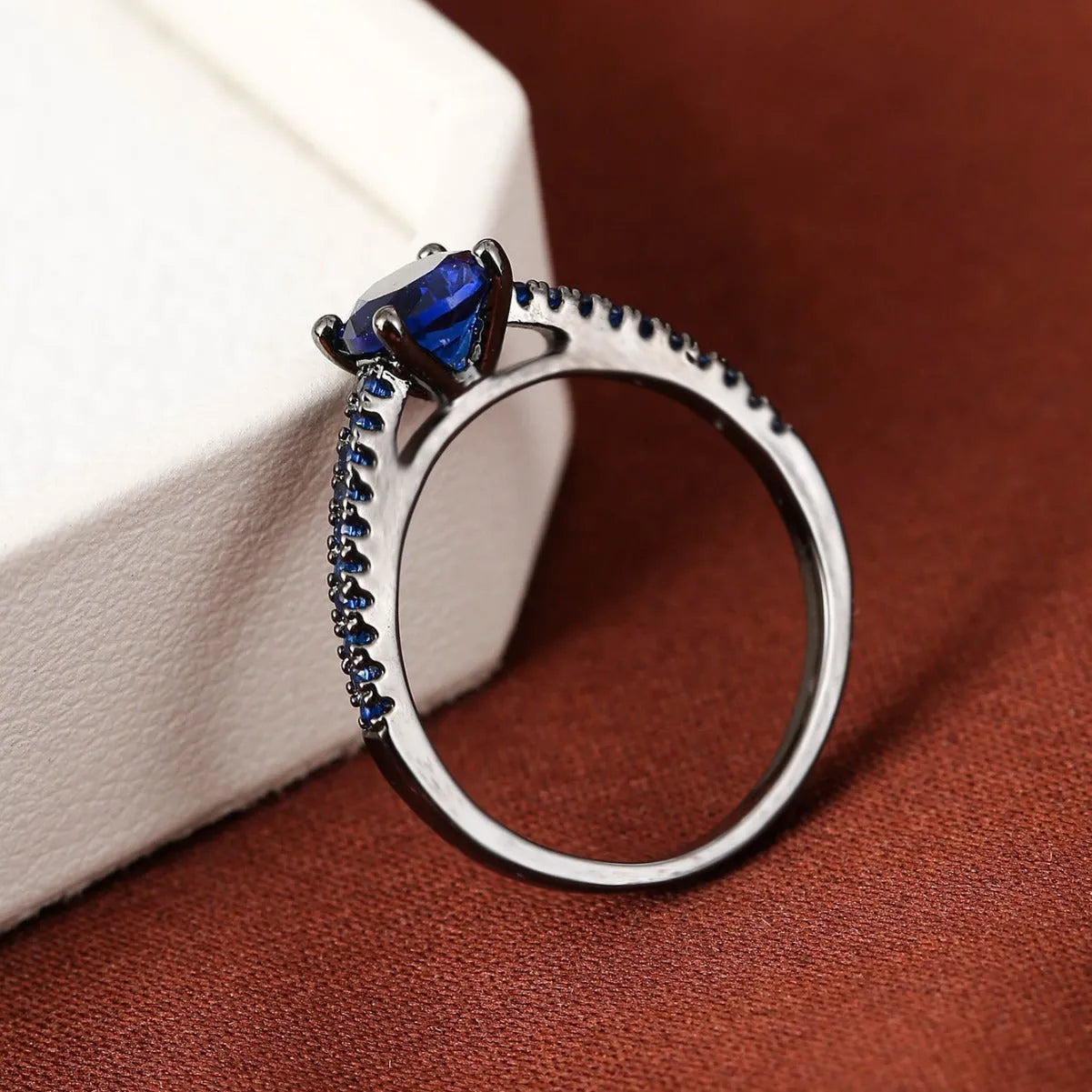 Geometric hexagon design copper zircon ring in various electroplated colours on a size guide.