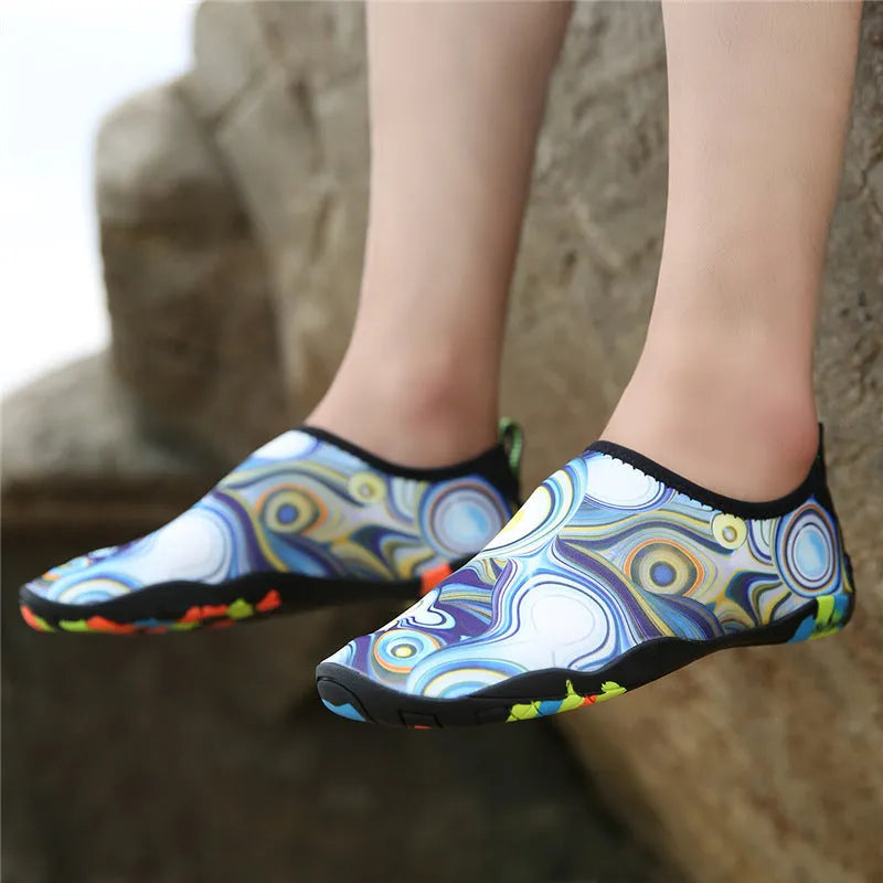 Blue and camouflage coloured beach wading shoes with Lycra uppers on a sandy background
