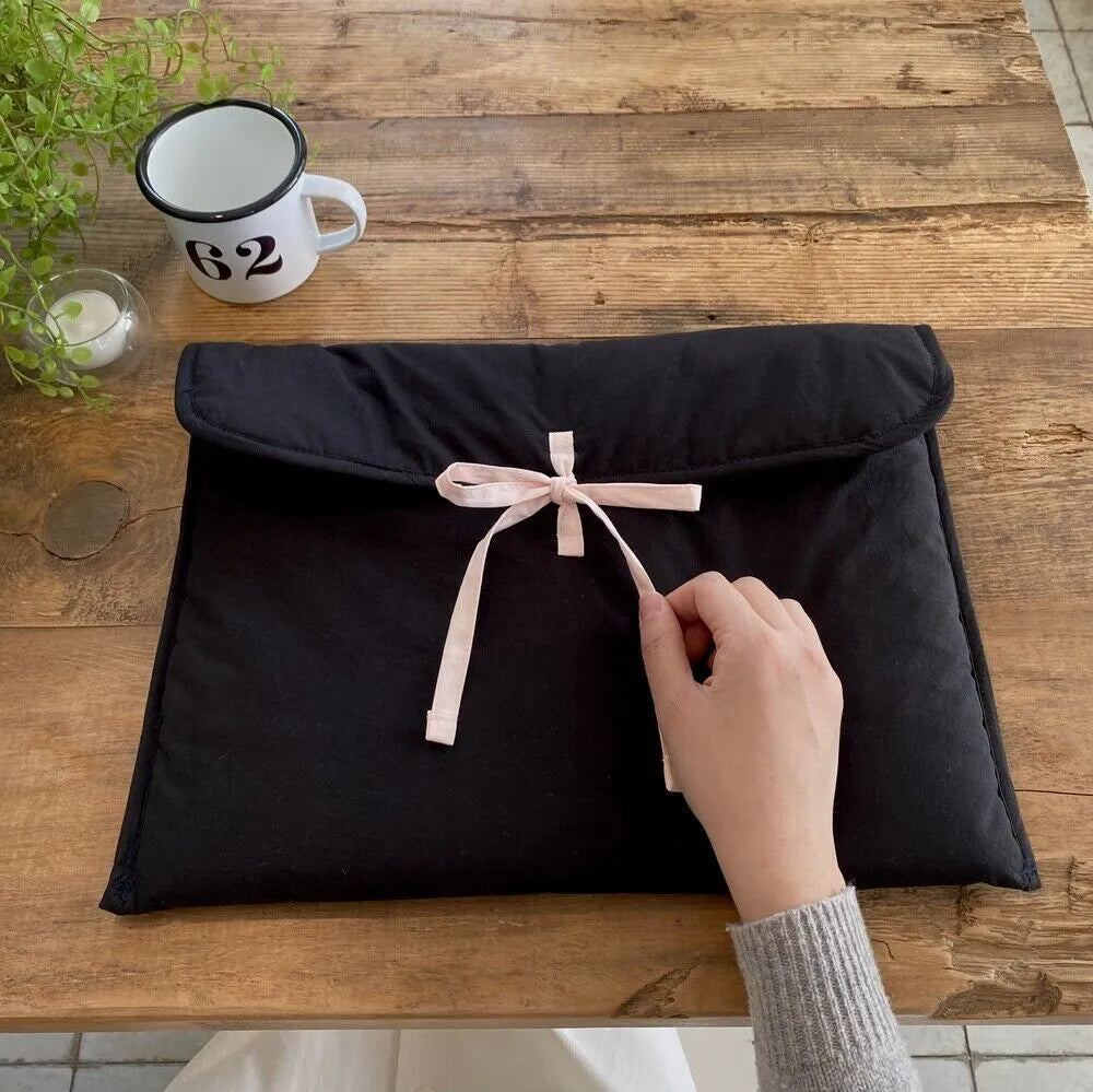 Women's black quilted computer bag with striped pattern and ballet bow detail