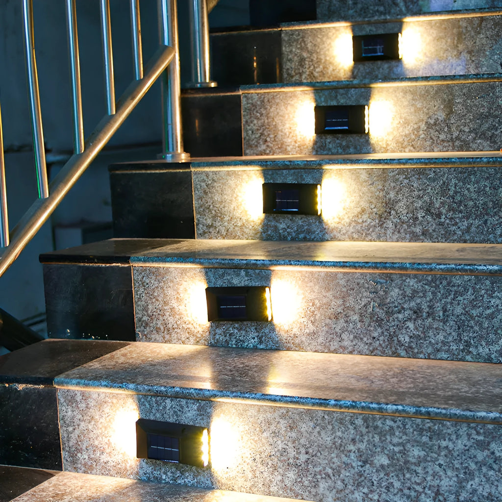 Small solar-powered black plastic outdoor wall light with LED up and down irradiation on a garden wall