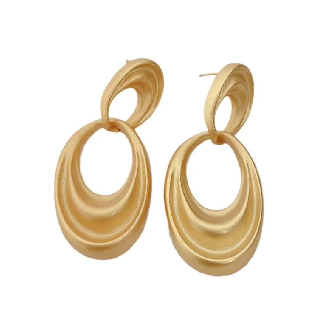 A pair of gold-toned double circle earrings with a textured quicksand finish on a copper base.