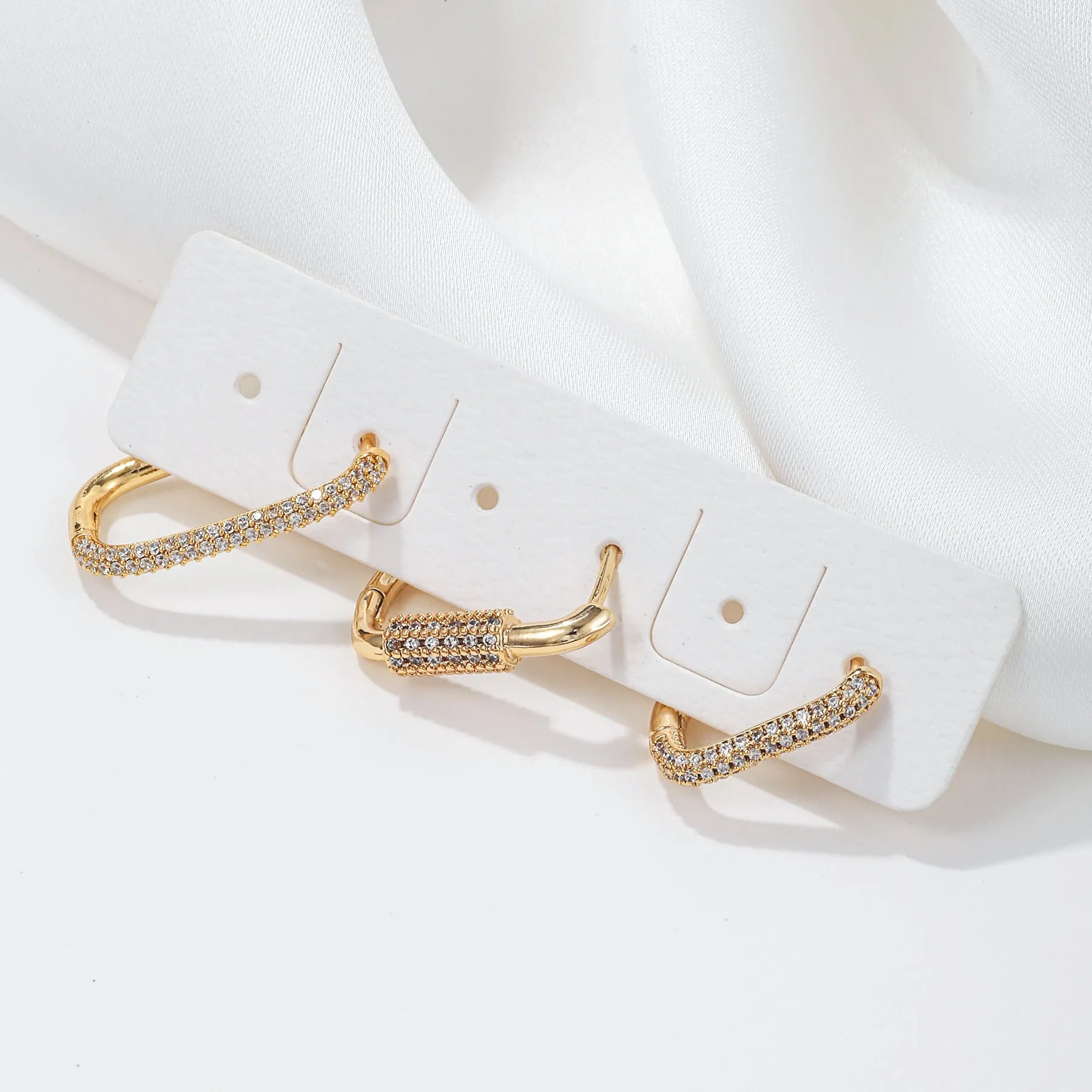 Three geometric ear clips with micro inlaid zircon detailing on copper in gold and white colours