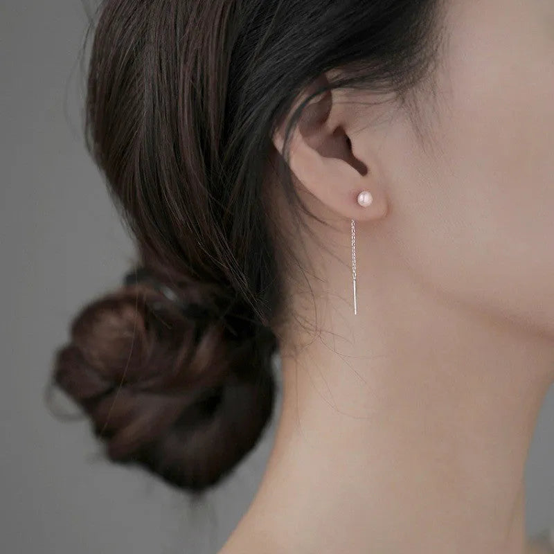 Sterling silver ear string with assorted small geometric and pearl charms on an alloy ear wire.
